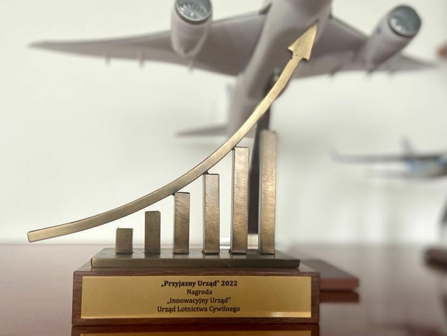 Statuetka "Przyjazny Urząd" na tle samolotu