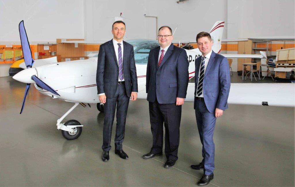 Na tle samolotu w hangarze trzej mężczyźni